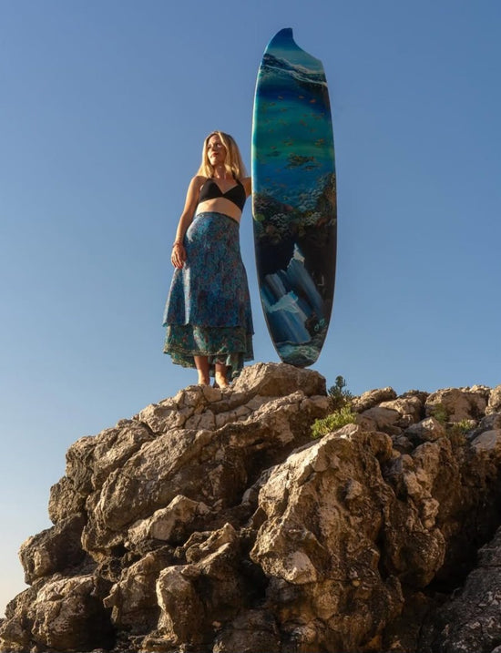 Wonder Surfboard by Angie Hickson shown on a coastal rock